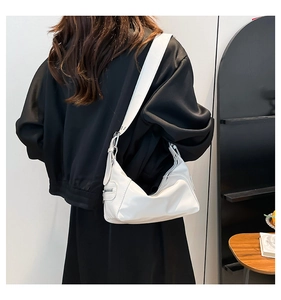 White minimalist hobo bag worn by a model, showing the half-moon shape and side zipper