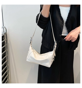 Close-up of white crescent shoulder bag with silver zipper detail and adjustable strap
