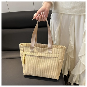 Macro detail of the beige corduroy tote bag showing woven texture and yellow side drawstring