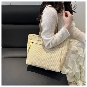 Close-up of woven tote bag with beige vertical stripes and light brown ribbon handle