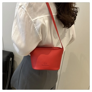 Détail du sac seau rouge en cuir grainé montrant le logo et la texture raffinée