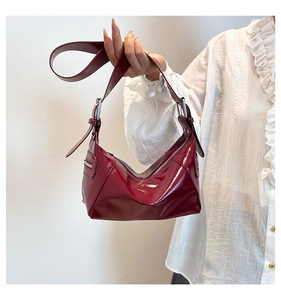 Detail of dark red patent leather shoulder bag showing glossy texture and side zipper
