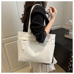 Detail of white woven tote bag showing side pocket and front zipper pocket on a model