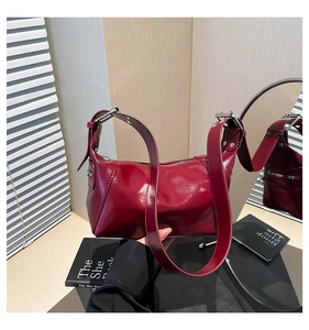 Detail of dark red patent leather bag with silver buckle and wide strap via mirror reflection