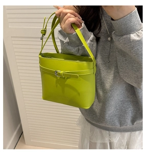 Dettaglio della borsa a tracolla in pelle verde neon con fibbia e logo in rilievo