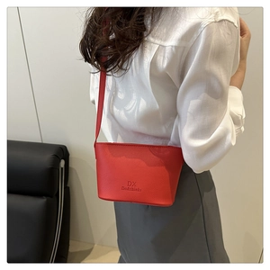 Detailed side view of a red pebble leather bucket bag shown on a model's shoulder