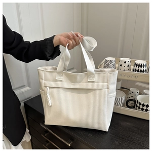 Macro detail of white corduroy tote bag showing vertical texture and zipper pocket