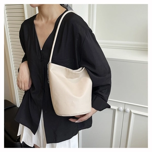 Detail of cream bucket bag with lychee texture leather and silver chain strap on shoulder