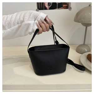 Détail du sac seau noir en cuir grainé avec logo DX et options de double bandoulière