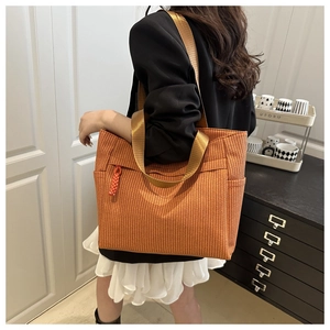 Detail of orange woven tote bag showing its dense texture and wide nylon strap on shoulder