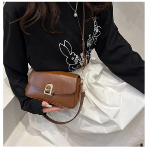 Détail d'un sac à bandoulière marron avec boucle métallique dorée en forme d'arche