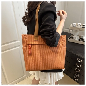 Side view of large orange-brown woven tote bag with shoulder straps worn by model