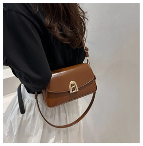 Détail d'un sac à bandoulière en cuir marron avec boucle dorée et fine bandoulière