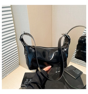 Detail of glossy black shoulder bag with silver hardware and adjustable strap