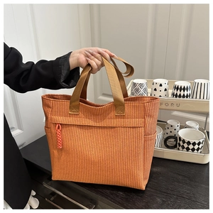 Detail of orange woven tote bag showing herringbone texture and side pocket design