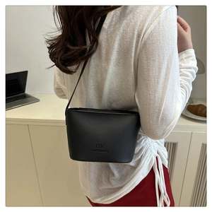 Detail of black pebbled leather bucket bag with brand logo and slim shoulder strap