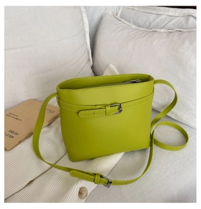 Detail of lime green litchi texture bucket bag with adjustable strap on white fabric