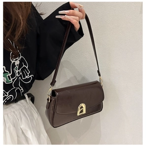 Détail du sac à main marron foncé avec boucle dorée et finition en cuir brillant