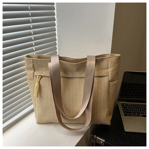 Detail of beige straw tote bag featuring woven texture and decorative yellow tassels