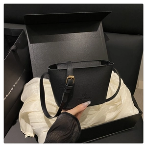 Close-up of black lychee grain leather bucket bag with DX logo in a premium gift box