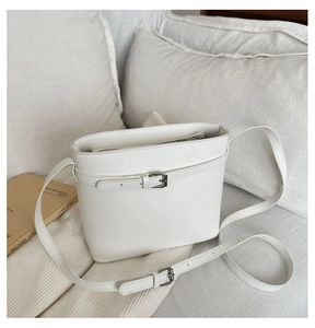 Detailed close-up of white lychee pattern bucket bag with decorative buckle and long strap