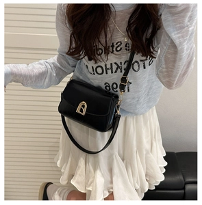 Sac bandoulière chic en cuir noir avec boucle dorée présenté sur un mannequin de mode