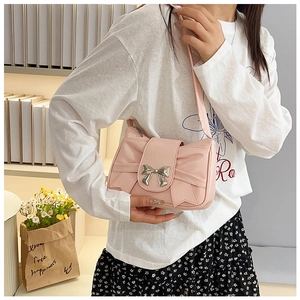 Détail du sac à bandoulière rose en forme de nœud avec boucle en métal et plis chic