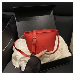 Close-up of red lychee leather bucket bag with gold hardware and brand logo detail