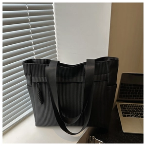 Close-up of black tote bag featuring vertical woven texture and wide shoulder straps