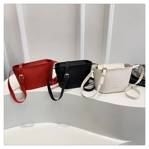 Close-up of bucket bags in red, black, and white featuring lychee leather and gold buckles