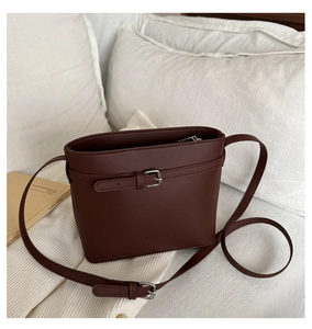 Detailed view of dark brown bucket bag with adjustable strap and silver metal hardware
