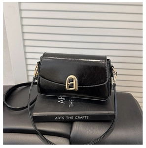 Vue détaillée du sac bandoulière en cuir verni noir avec boucle métallique en fer à cheval