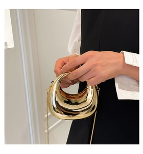 Macro shot of high-shine gold metallic crescent bag with elegant chain strap detail