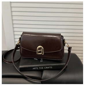 Détail du sac en similicuir marron foncé avec boucle dorée en arche et texture cirée