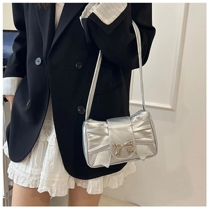 Close-up of silver metallic bow shoulder bag with pleated texture and bow buckle
