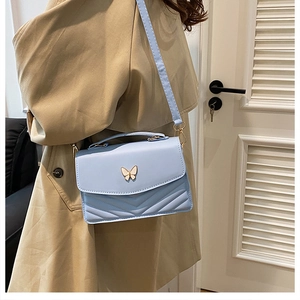 Light blue crossbody bag featuring a golden butterfly clasp and elegant V-shaped stitching