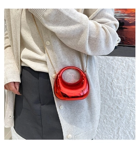 Close-up of red patent leather mini bag with round handle and gold chain strap