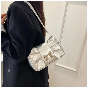 Close-up of a silver bow shoulder bag with metallic finish on a model in a black blazer