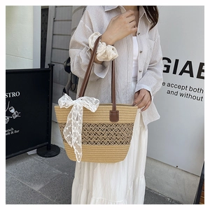 Detail of beige woven tote bag with lace bow and brown leather straps on striped outfit
