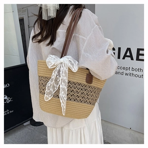 Detail of straw tote bag featuring white lace bow and brown leather straps for summer
