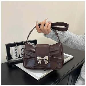 Detail of dark brown leather handbag featuring pleated bow design and silver metal hardware