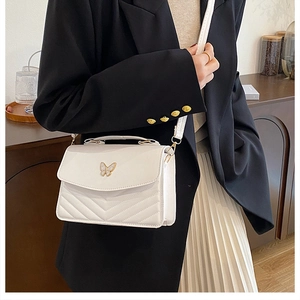 Close-up of a white V-quilted crossbody bag with a delicate gold-edged bow on a model
