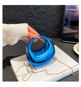 Detail of blue metallic hard shell evening bag with gold chain and circular handle