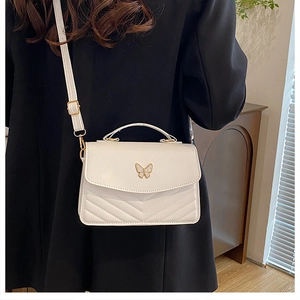 Detail of cream white crossbody bag with chevron pattern and metal butterfly clasp
