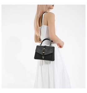 Détail du sac à main noir montrant le rabat en strass brillant et la boucle dorée