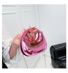 Detail of a shiny metallic pink crescent bag featuring a sleek mirror finish and gold chain