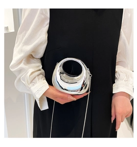 Detail of silver metallic dumpling bag with round handle and metal chain on model