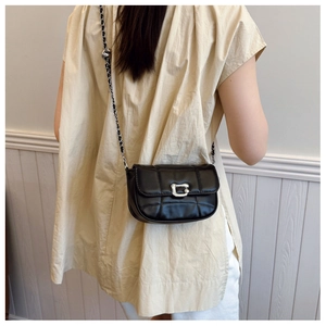 Detail of black quilted leather shoulder bag with silver chain strap and metal buckle