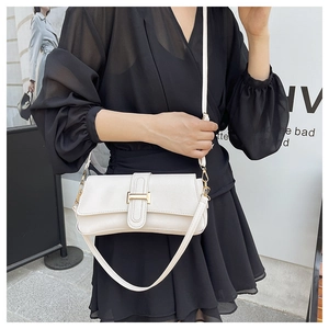 Detailed view of the white faux leather shoulder bag with golden metallic buckle on model