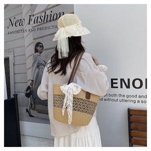 Detail of woven straw handbag with white lace bow and matching sun hat on a model